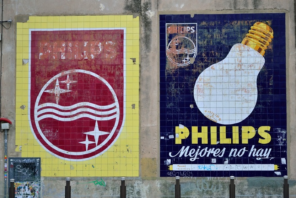 Panneau publicitaire en céramique Philips avec une ampoule et le texte « PHILIPS Il n’y a pas de mieux », à côté d’un autre panneau avec le logo, rue Blanquerías à Valence, identité graphique urbaine