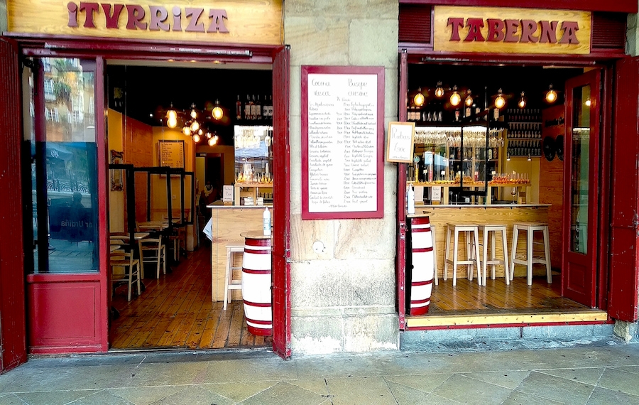 Façade de la Taberna Iturriza sur la Plaza Nueva de Bilbao, avec les panneaux « ITURRIZA » et « TABERNA » sur les portes, un exemple d’identité graphique urbaine.