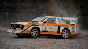 Image générée par IA d’une voiture de rallye classique avec des enveloppes de course orange, blanches et turquoises dérapant sur une piste de gravier.